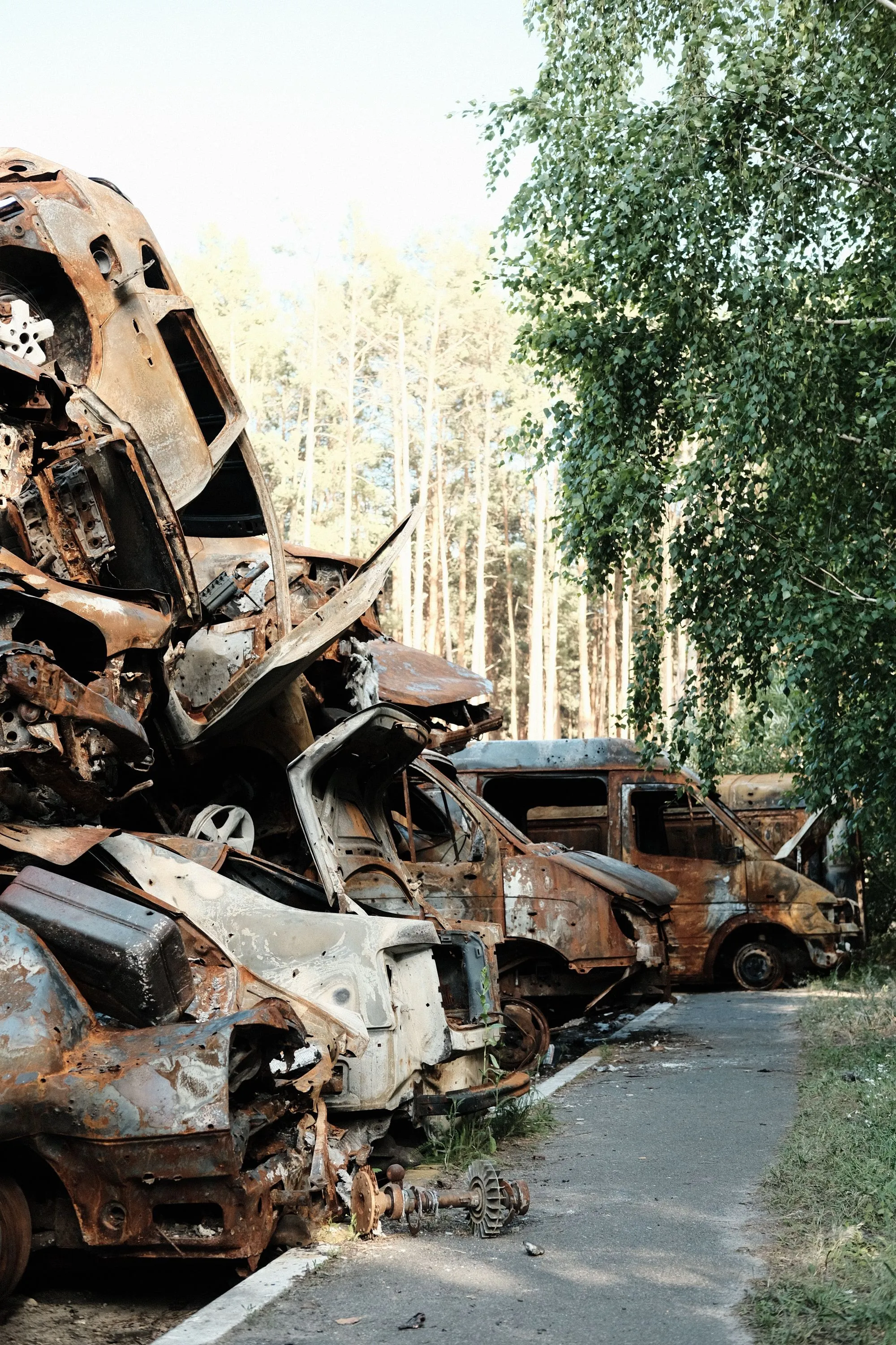 Rusted, wrecked cars stacked several high in an outdoor yard.